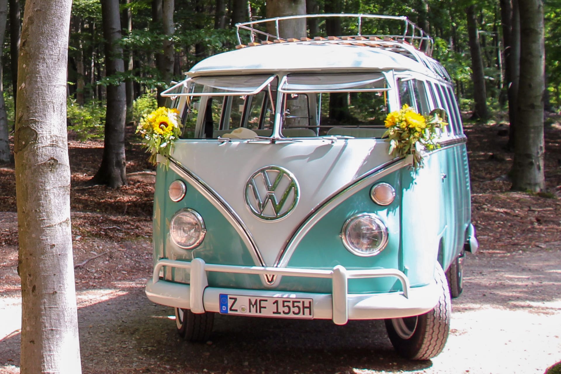 VW T1 Bulli im Wald mit Echtblumen Dekoration Sonnenblumen an den Außenspiegeln und Ausstellfenster