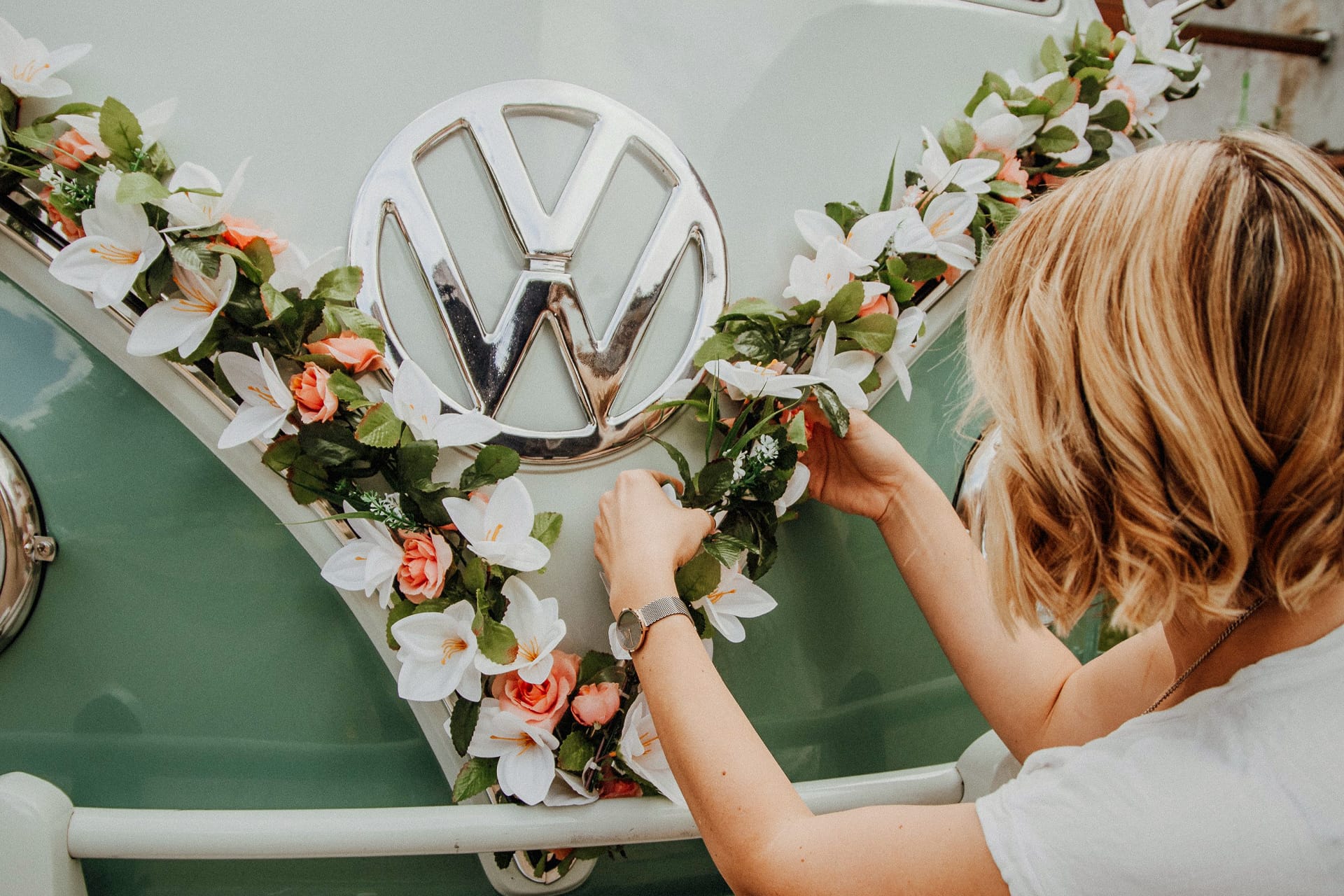 Autodekoration Standard mit Kunstblumen Girlande mit apricot farbene Rosen und weißen Blüten. VW Zeichen chrom